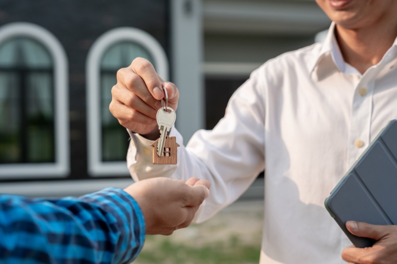 A hand passes house keys to another person